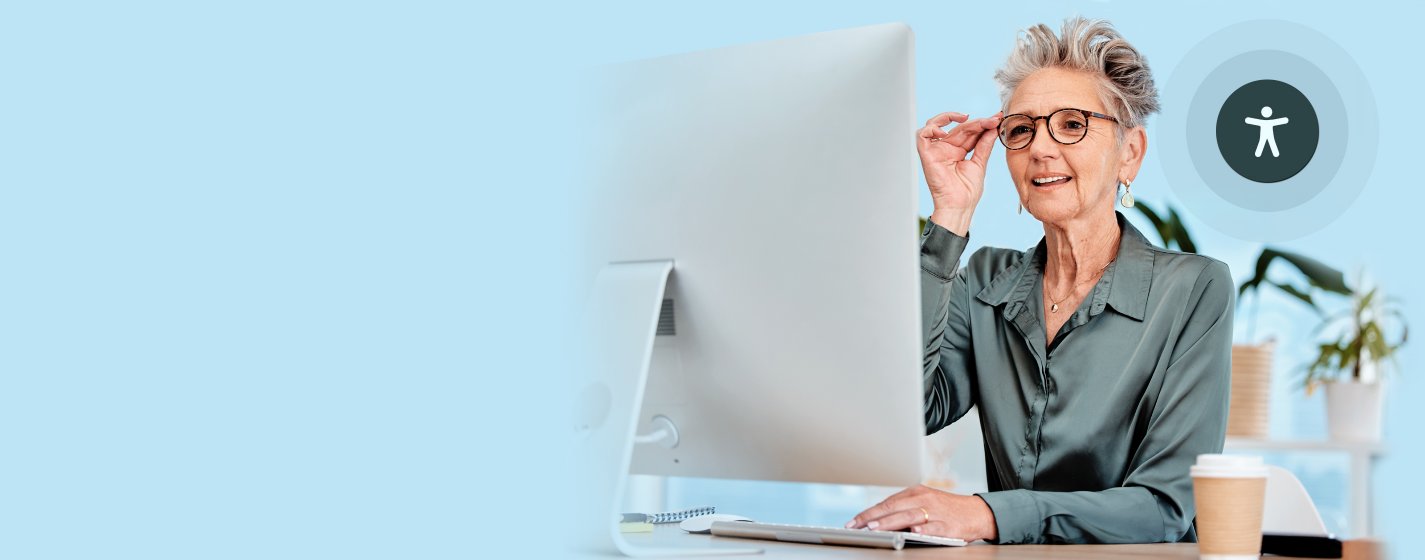 Ältere Dame mit dicker Brille vor einem PC.